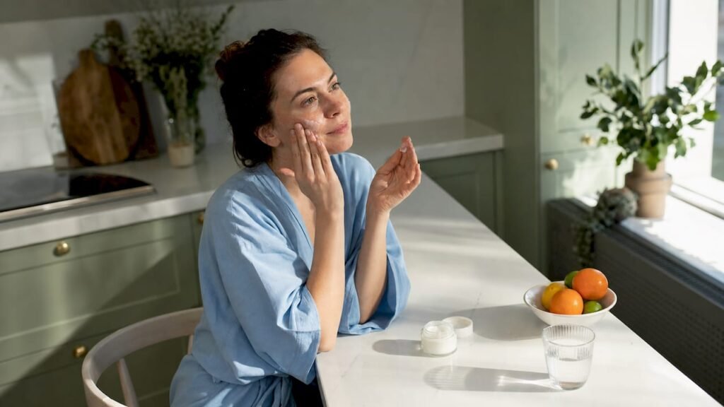 Woman applying moisturizer to face at vanity